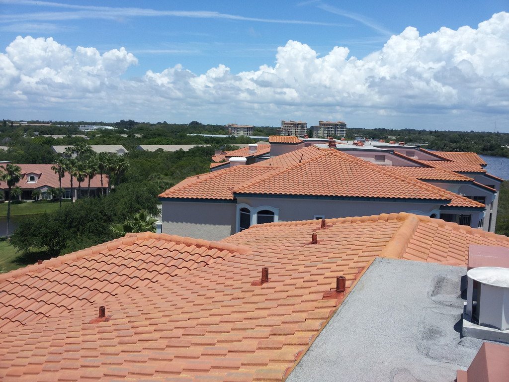 The same condominium barrel tile roof after cleaning, now clean terracotta, with the cleaned roofs and the waterway behind it.