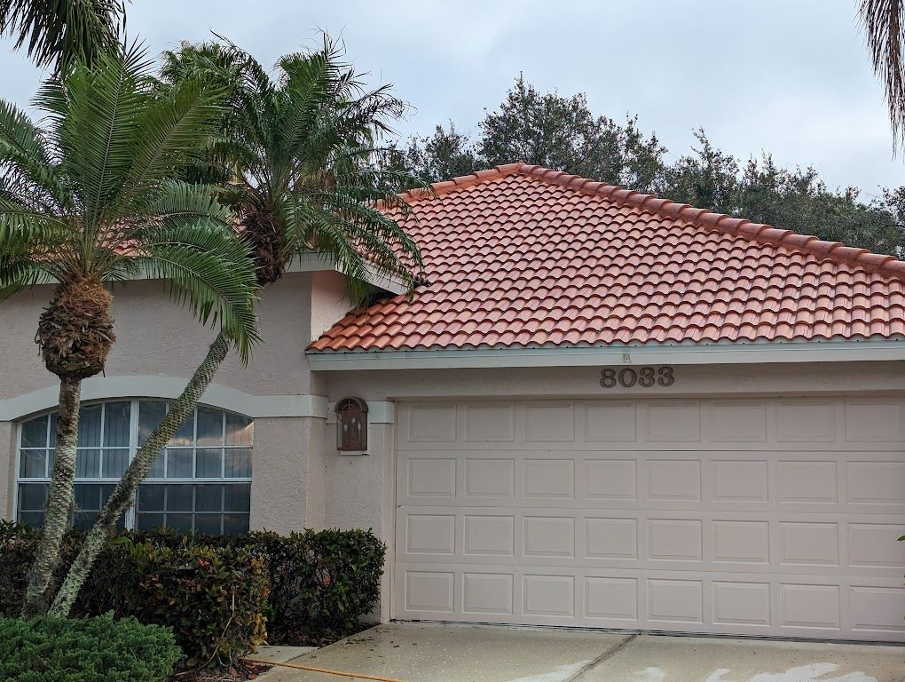 Clean terracotta barrel tile roof on a single-storey Florida home with palms out front.