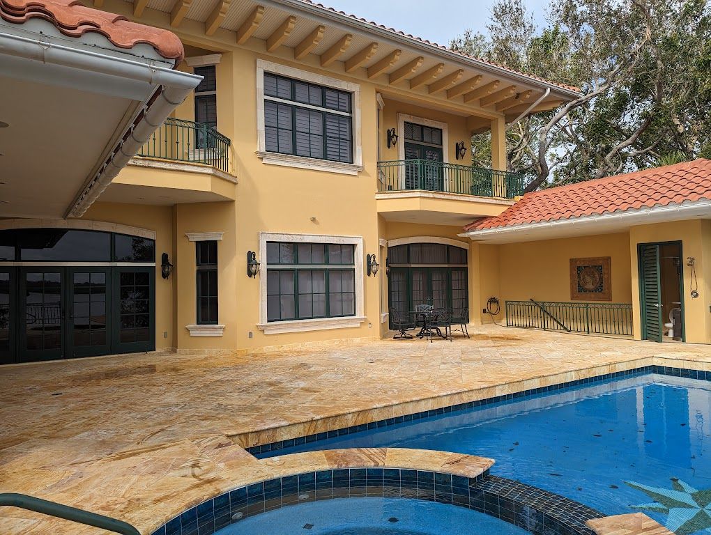 Travertine pool deck, spa and terracotta tile roof at a waterfront home after cleaning.